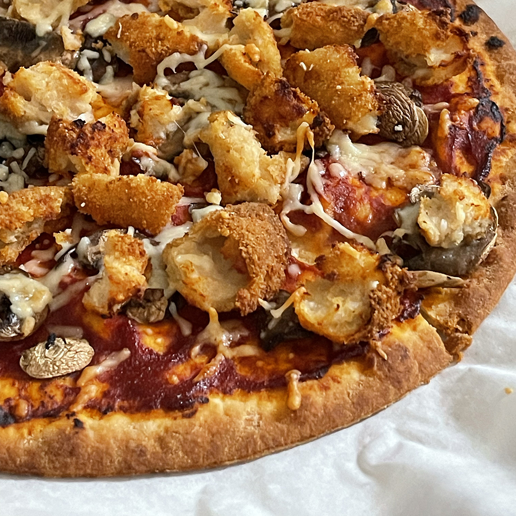 A pizza with mushrooms and cheese and other condiments.