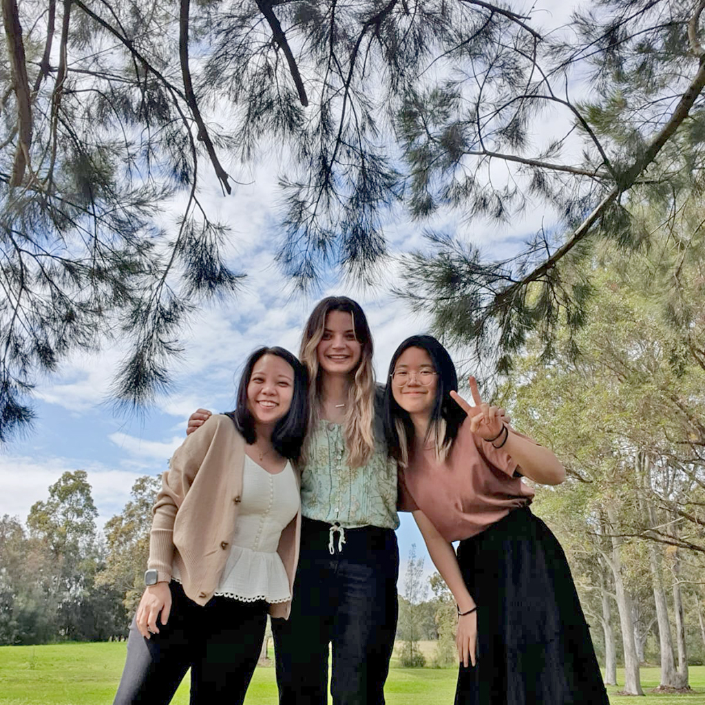 A group of three women standing under a tree